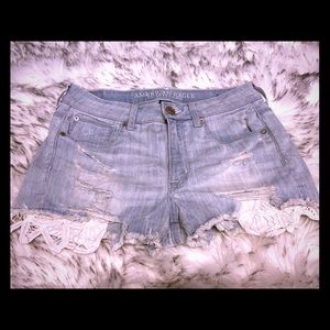 Blue Jean shorts that have white lace pockets